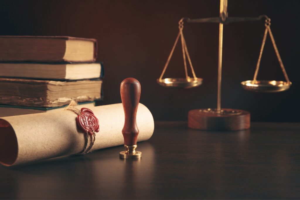 The scales of justice alongside a scroll stamped with a wax seal.